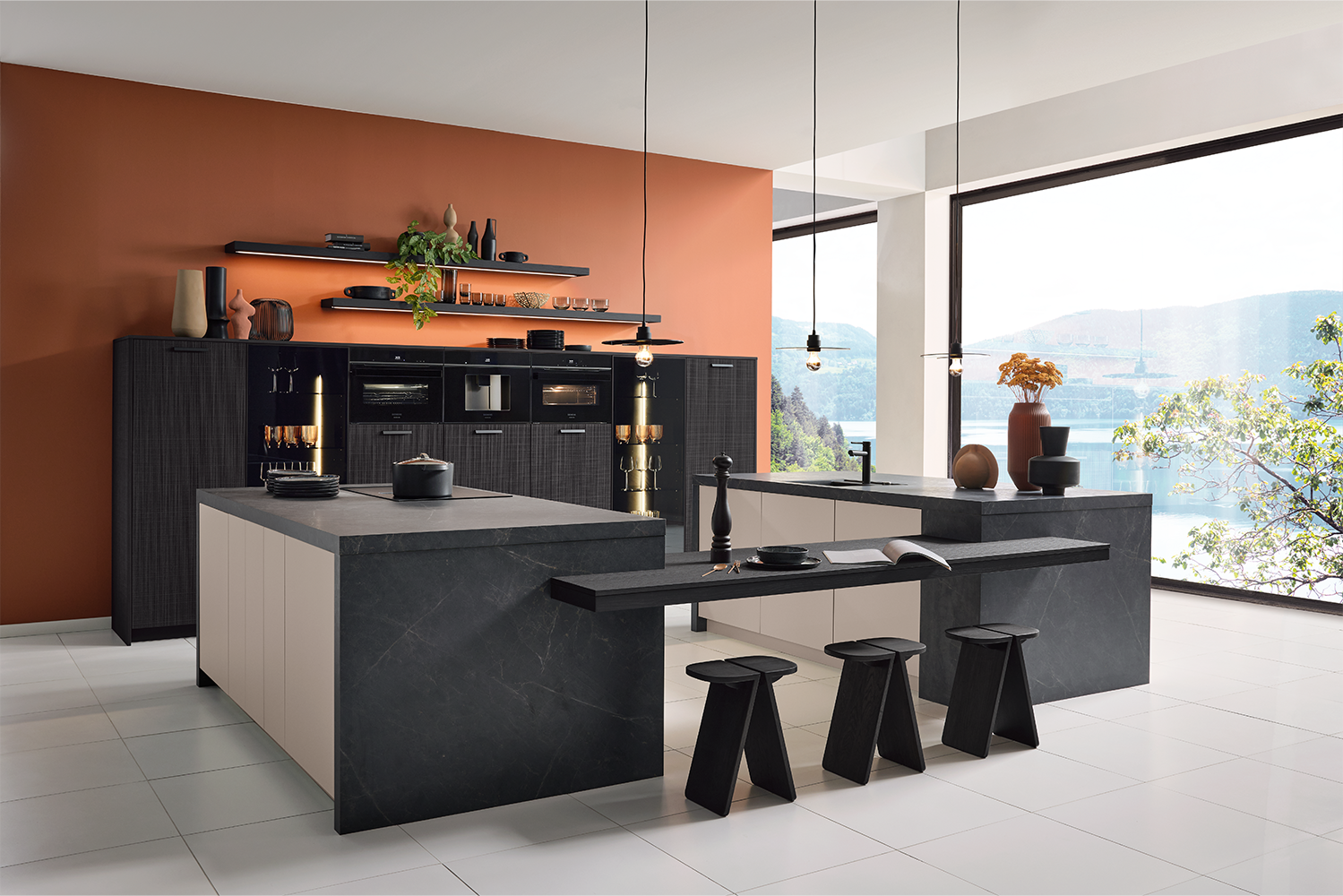 Elegant kitchen interior by pronorm featuring island with seating, built-in appliances and panoramic lake view.